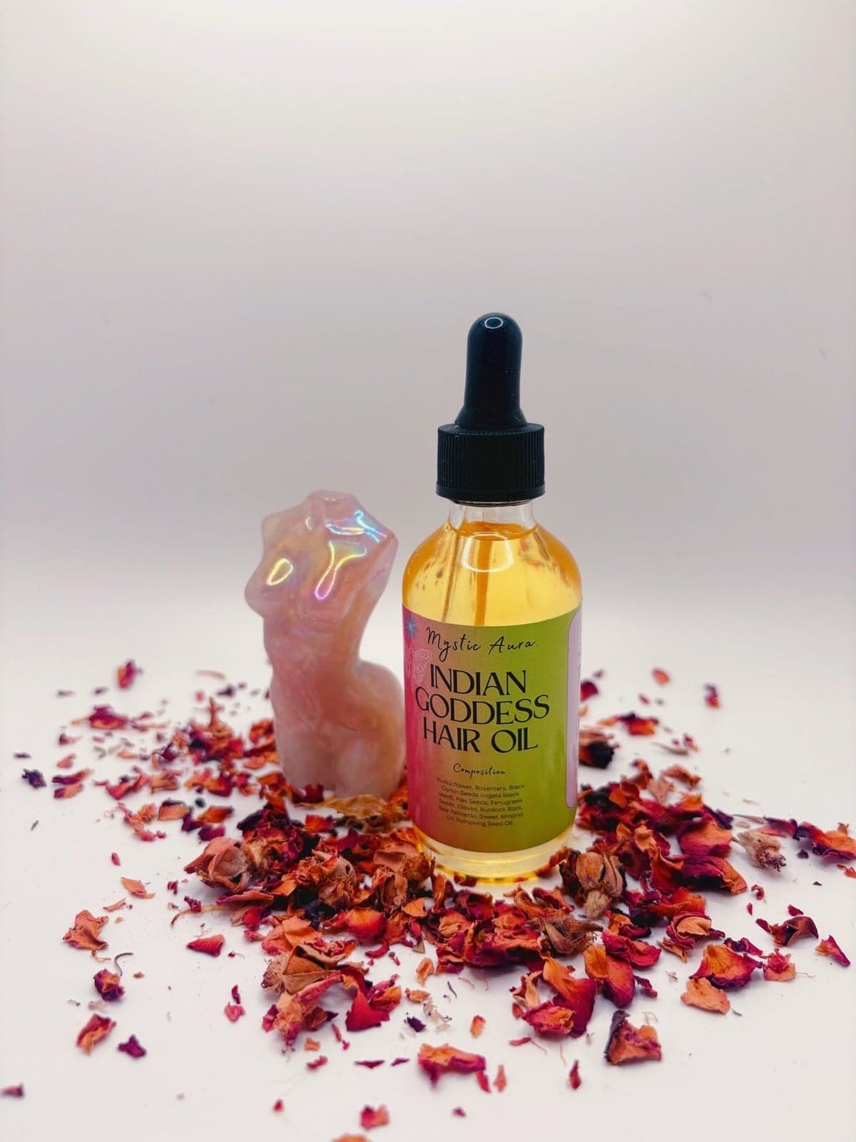 Two bottles of Indian Goddess Hair Oil on rose petals